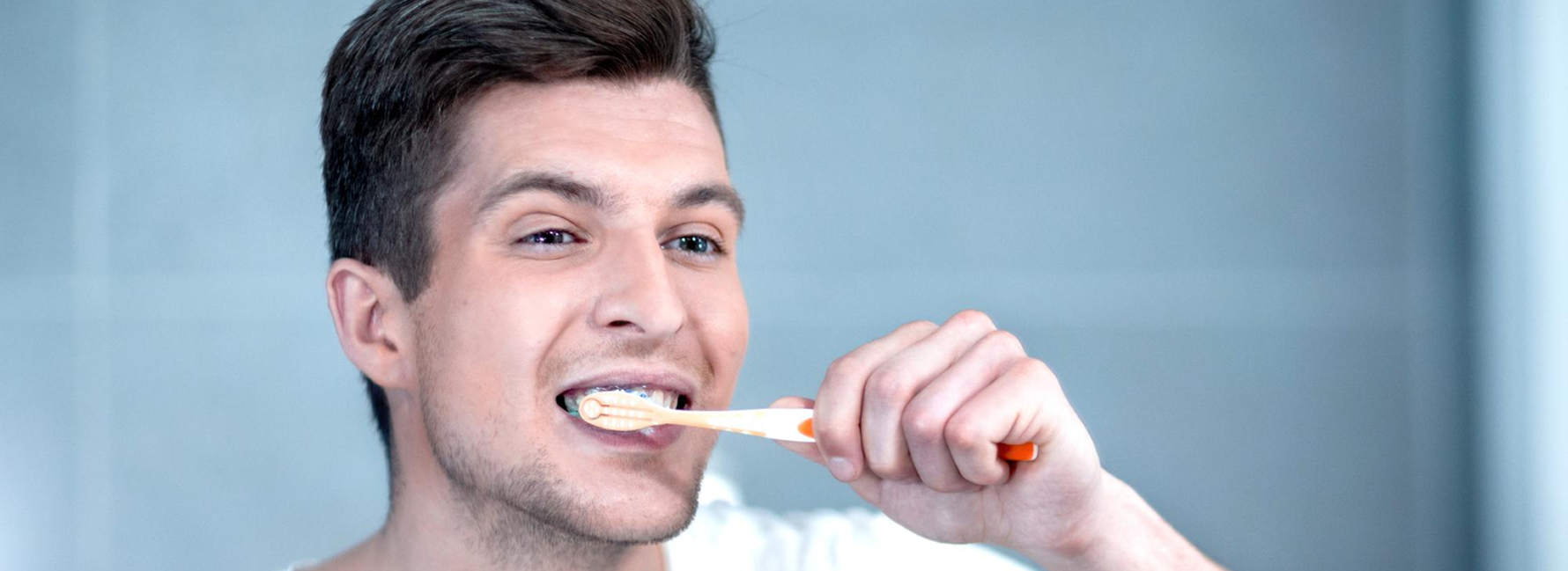 Person brushing teeth with excessive pressure leading to enamel wear and gum recession